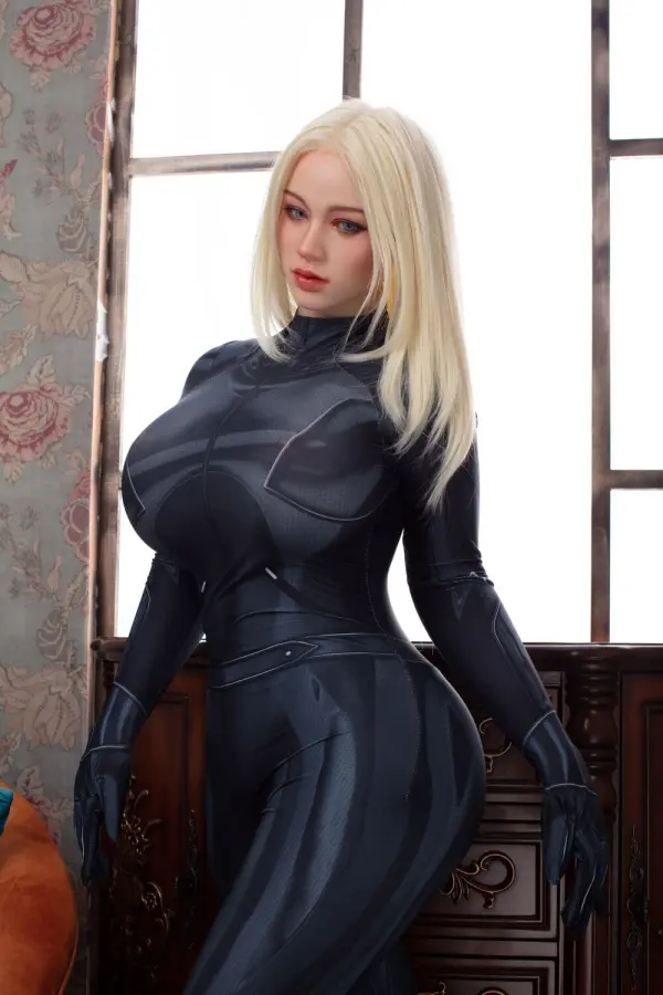Nova, eine 162cm TPE Sexpuppe, zeigt langes blondes Haar und ein J-Körbchen in einem engen schwarzen Bodysuit.